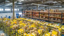 Grand entrepôt de stockage avec des rayonnages remplis de cartons et de bacs jaunes