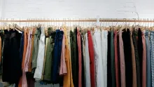 Longue tringle de vêtements colorés alignés sur des cintres devant un mur blanc