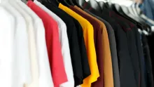 Rangée de t-shirts de couleurs variées suspendus sur des cintres
