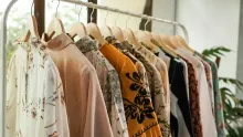 Portant blanc chargé de blouses et de vêtements clairs près d'une fenêtre