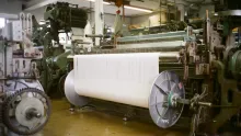 Métier à tisser industriel avec un grand rouleau de tissu blanc dans une usine textile