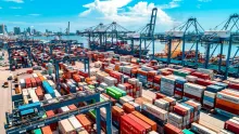 Terminal portuaire avec des piles de conteneurs colorés et des grues sous un ciel bleu