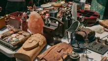 Table de brocante couverte d'objets anciens, de bibelots en bois et de vaisselle