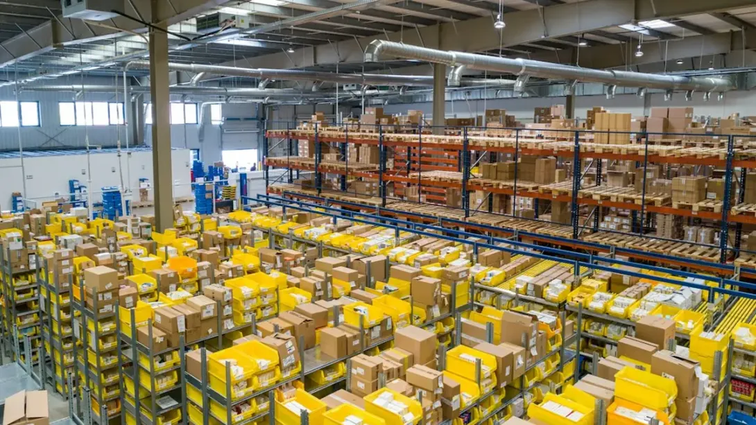 Grand entrepôt de stockage avec des rayonnages remplis de cartons et de bacs jaunes