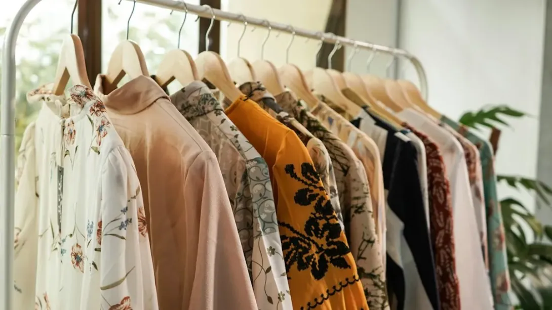 Portant blanc chargé de blouses et de vêtements clairs près d'une fenêtre