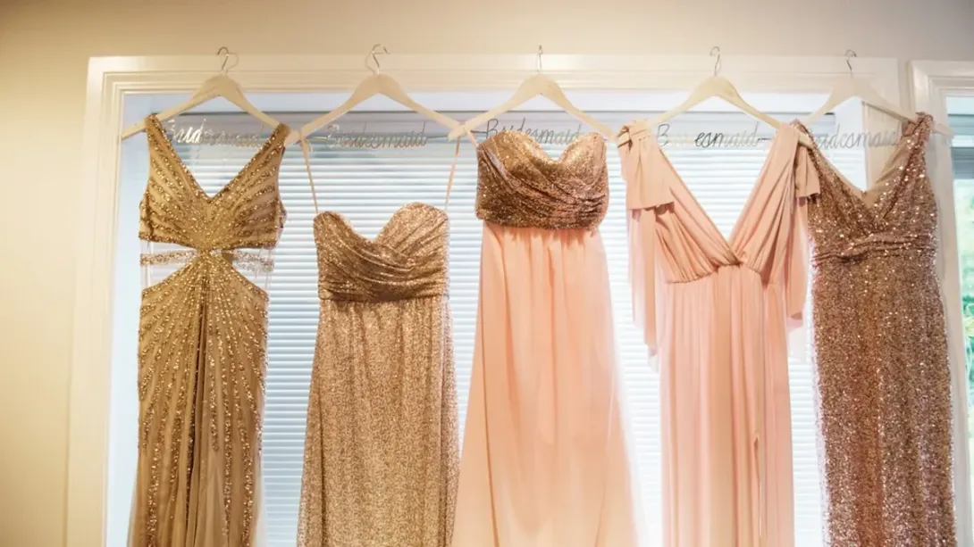 Robes de soirée dorées et rose pâle suspendues à des cintres